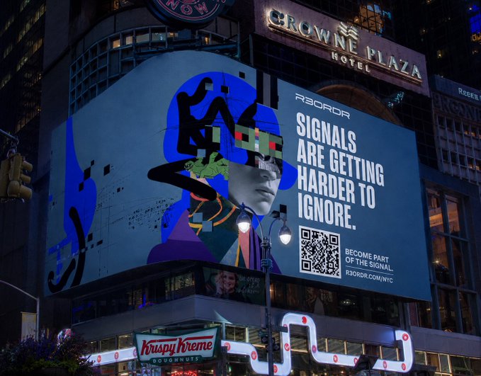 A massive digital billboard in Times Square displays R3ORDR's bold campaign for NFT NYC, featuring striking graphic art of a figure in futuristic sunglasses and a virtual reality headset alongside the message "SIGNALS ARE GETTING HARDER TO IGNORE," complete with a QR code directing viewers to R3ORDR.COM/NYC, signaling the brand's high-profile arrival in New York City. The "Crowne Plaza Hotel" sign glows above the display, anchoring the scene in the iconic Manhattan location three weeks before the NFT conference.