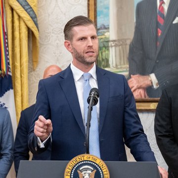 Eric Trump stands at a podium bearing the Presidential Seal, speaking into a microphone in what appears to be the Oval Office. The image accompanies his statement to WOLF Financial predicting that cryptocurrency will outperform the traditional financial system.