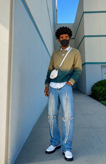 A young man wearing a black mask, an olive and teal color-block sweater, a white crossbody bag, and distressed blue jeans standing in an outdoor walkway.