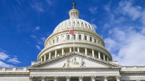 The U.S. Capitol dome with an American flag flies overhead against a bright blue sky, symbolizing the Senate's legislative progress.

The image connects to the post by visually representing the U.S. Senate, which the announcement references as the body planning to vote on the CLARITY Act for crypto assets after the summer recess.