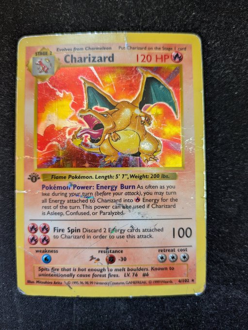 A heavily worn, holographic Charizard Pokémon trading card from the Base Set (4/102, Stage 2, 120 HP) featuring the 'Fire Spin' attack.