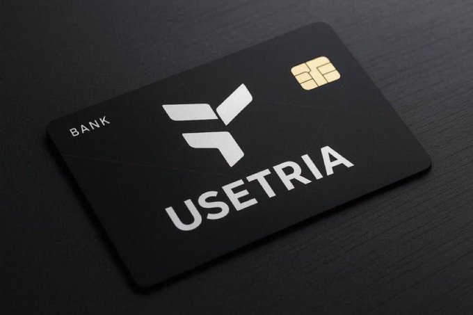 The image features a black credit card with white text that reads "useTria" written in capital letters. The credit card has a gold stripe at the bottom right corner. The background of the image is dark, which makes the credit card stand out prominently.