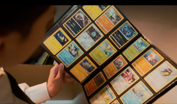 An over-the-shoulder view of a child holding open a large binder filled with a collection of Pokémon trading cards.
