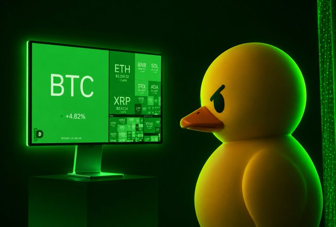 A yellow rubber duck looks at a computer monitor displaying cryptocurrency tickers including BTC (+4.82%), ETH, BNB, SOL, TRX, ADA, and XRP, all bathed in green light.