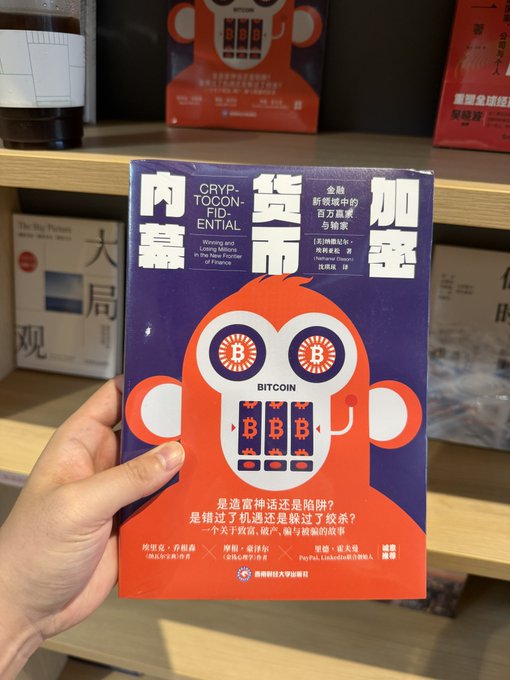 A hand holding a Chinese-language book titled '加密货币内幕' (Cryptoconfidential) about Bitcoin and losing money in the new frontier of finance, published by 贵州财经大学出版社.