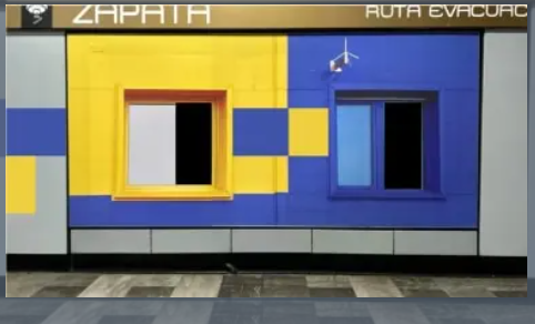 The image features a colorful building with yellow, blue, and white walls. There are two windows on the side of the building - one is open, while the other has its shutter closed. The text "zapatia" can be seen above the building, which might indicate that it's an art gallery or a store named after the artist Z Patrizio.