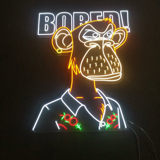 A neon sign depicting a stylized angry monkey wearing a Hawaiian shirt with red flowers, positioned below the text 'BORED'.