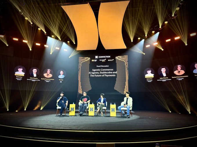 Four panelists participate in a stage discussion at "Conviction Vietnam 2026" on the topic "Agentic Commerce: AI Agents, Stablecoins and The Future of Payments," with their headshots and names displayed on screens behind them under dramatic yellow stage lighting. The image visually supports the post's theme by capturing the very conversation it describes about AI-driven commerce and emerging payment infrastructure.