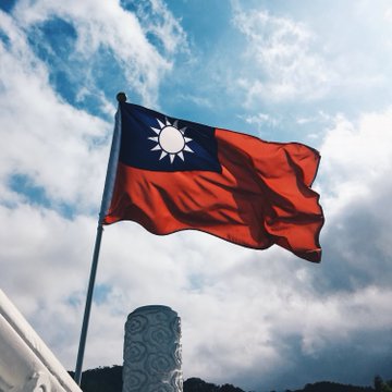 The flag of Taiwan waves against a cloudy sky, symbolizing the country's forthcoming crypto regulations like the "Travel Rule." This visual connection highlights Taiwan's move towards global regulatory standards in the digital asset space.