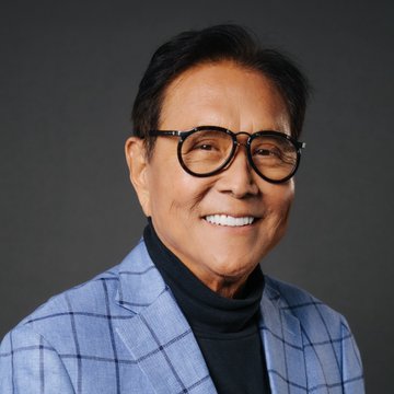 Robert Kiyosaki, the well-known personal finance author of "Rich Dad Poor Dad," smiles warmly in a professional portrait, wearing round glasses and a blue plaid blazer over a black turtleneck. His image accompanies his bullish Bitcoin prediction, lending visual authority to his forecast that even a fraction of a Bitcoin will become priceless in two years.