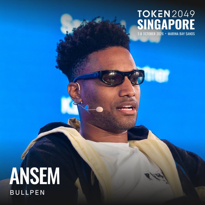 A promotional image for TOKEN 2049 Singapore (7-8 October 2026 at Marina Bay Sands) featuring "ANSEM" from "BULLPEN" wearing dark sunglasses and a headset microphone against a blue backdrop, matching the caption's announcement of speaking at the Singapore crypto conference.