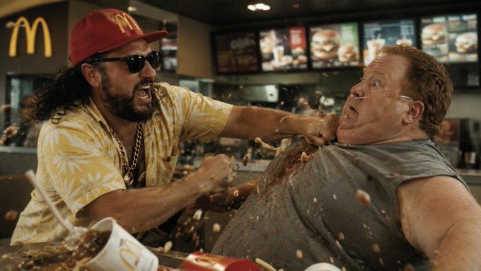 The image depicts a chaotic scene inside a McDonald's, featuring a man in a yellow Hawaiian shirt and red McDonald's cap aggressively grabbing another man by the collar, with food splattering mid-air amid visible menu boards and the iconic "M" logo. The accompanying post referencing "$Pauly" and "$COPE" suggests this is likely promotional material for a cryptocurrency or meme coin, using the dramatic clash imagery to grab attention with the promise that "what's coming next may shock you."