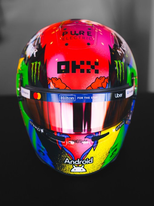 A vibrant racing helmet featuring "OKX," "Pure Electric," "Monster Energy," "Hilton For The Stay," "Uber," and "Android" branding, showcasing the colorful new "Madring" lid design.