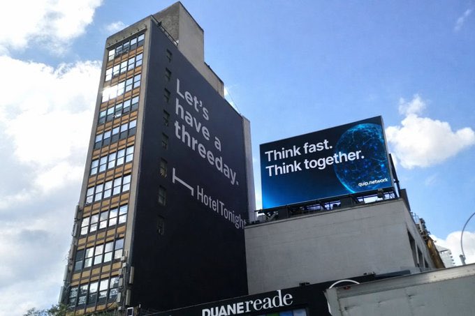 A tall building with a large advertisement reading 'Let's have a threeday. Hotel Tonight' next to a billboard displaying 'Think fast. Think together.' for SKIP network.