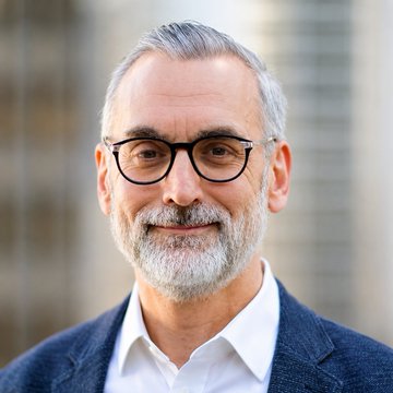 A portrait of a gray-haired man with glasses and a beard, likely Stuart Alderoty, Ripple's Head of Legal Affairs, who is advocating for the approval of the Clarity Act to prevent exploitation in unregulated crypto markets.