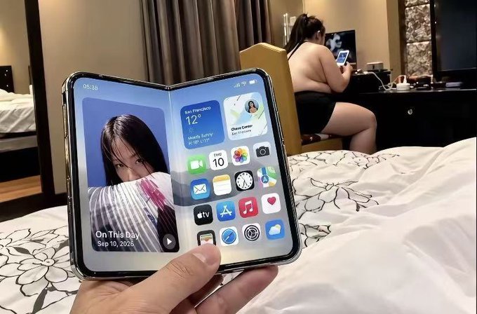 A person holds a foldable smartphone displaying a lock screen with 'On This Day, Sep 10, 2025' and widgets for San Francisco weather, while a woman sits in the background.
