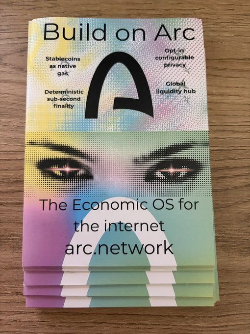 Stack of promotional brochures for Arc Network titled 'Build on Arc — The Economic OS for the internet,' featuring the Arc logo and a stylized face with glowing eyes.