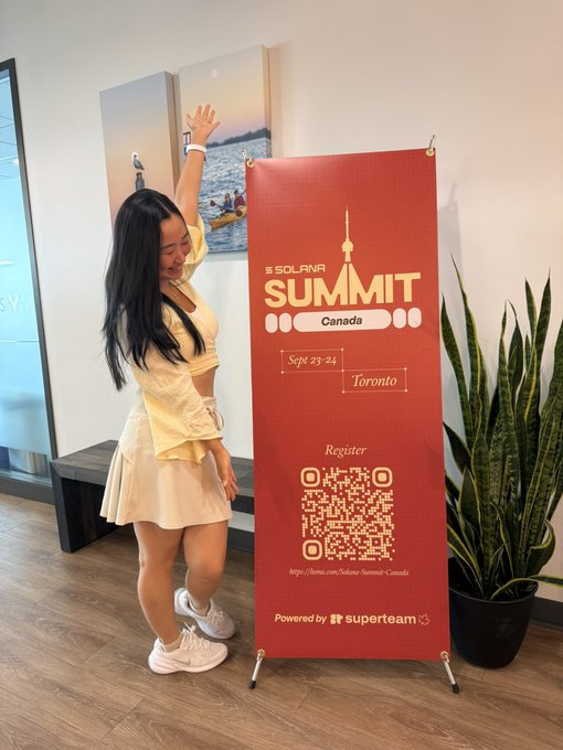 A woman poses next to a red 'SOLANA SUMMIT Canada' banner for an event in Toronto on Sept 23-24, featuring a registration QR code and 'Powered by superteam' branding.