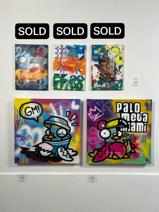 Five colorful, cartoonish paintings featuring frog-like characters are displayed on a white gallery wall. The top three are marked with 'SOLD' signs, and the bottom right painting includes the text 'PALOMETA JAM!'.