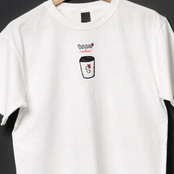 A plain white t-shirt hanging on a hanger, featuring a small embroidered graphic of a character with text that appears to read 'bean candy'.