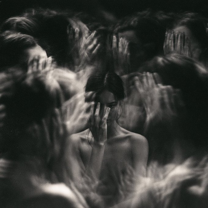A black-and-white image showing a central woman shielding her face with her hand while surrounded by a crowd of hands reaching toward her, visually echoing the post's message about the overwhelming noise of voices that don't deserve attention.