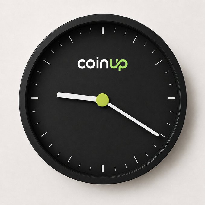 The image features a black clock with white numbers and hands, displaying the time as 12:30. The clock has a green "coinup" logo at the top center of its face. Below the clock, there's text that reads "GM 把握今天的每一个关键时刻", which translates to "CoinUp" in English. The phrase "Focus on what is in the image and how it relates to the post..." suggests that the image might be related to a discussion or promotion about CoinUp, possibly as part of an advertisement or social media post.
