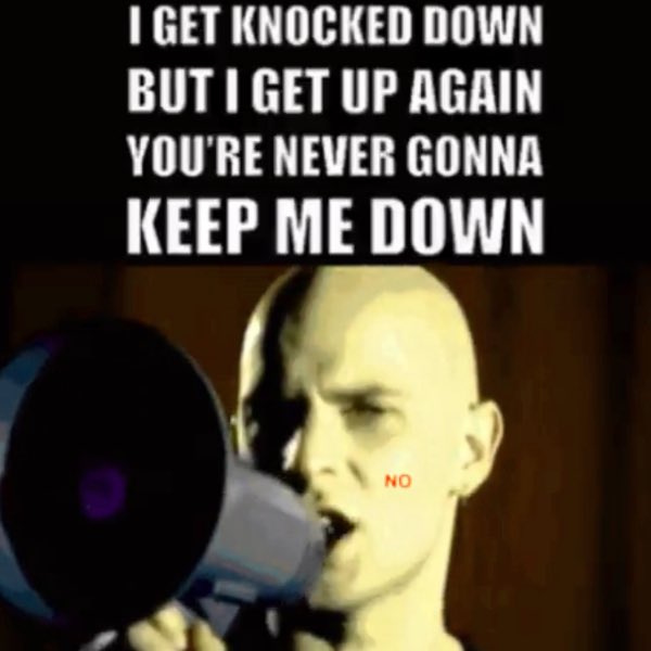 A low-quality meme image of a bald man shouting into a megaphone with the lyrics 'I GET KNOCKED DOWN BUT I GET UP AGAIN YOU'RE NEVER GONNA KEEP ME DOWN' displayed above him and the word 'NO' in red on his cheek.