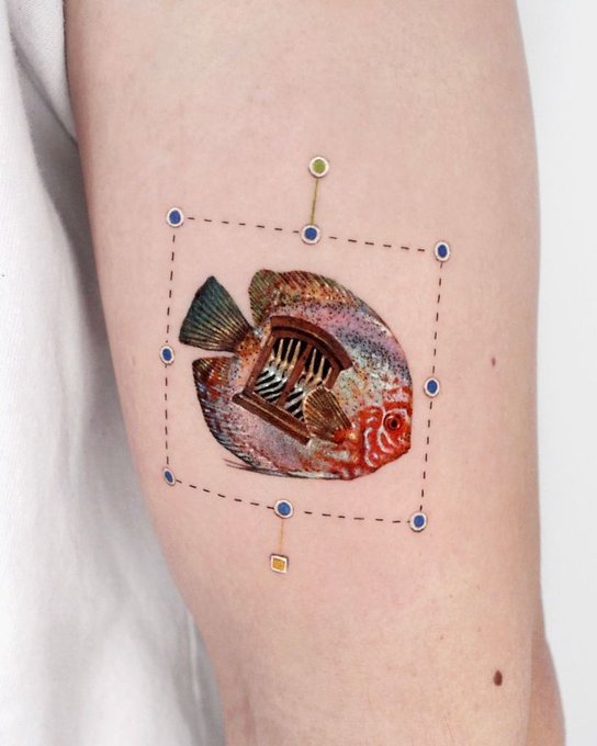A tattoo on an arm featuring a surrealist image of a fish with a doorway revealing stairs inside its body, framed by a dashed square with blue and green pins.