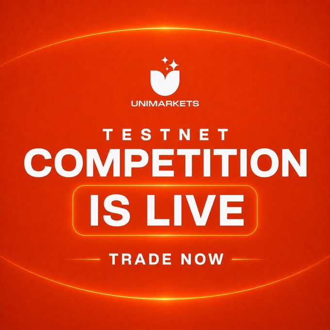 The image is a bold red promotional graphic for Unimarkets, featuring the company's white tulip-shaped logo with sparkles above "UNIMARKETS" text. Large white text announces "TESTNET COMPETITION IS LIVE" with "IS LIVE" highlighted in a glowing yellow-bordered button, followed by a "TRADE NOW" call-to-action, visually reinforcing the post's message about a $50,000 USDC testnet trading competition and driving users to testnet.unimarkets.io.