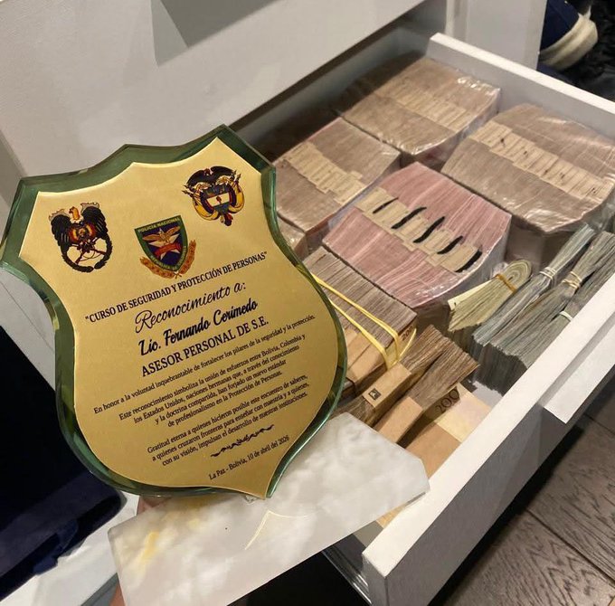 A glass plaque from a "Curso de Seguridad y Protección de Personas" in Bolivia recognizes Lic. Fernando Corimayo as an "Asesor Personal de S.E." (personal advisor to the president), alongside stacks of cash visible in an open drawer. The image reinforces the post's claim that the CIA makes cash payments to its assets, as the currency appears to be staged alongside an award tied to Bolivian presidential security circles.