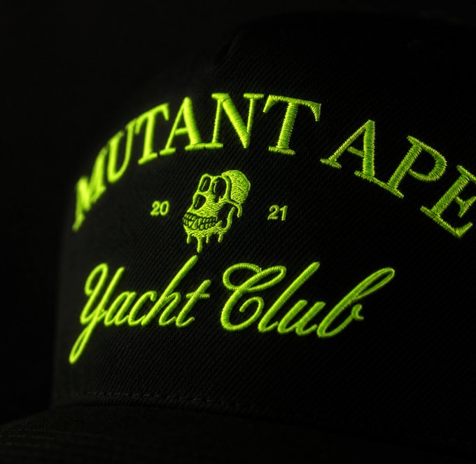 A close-up of a black cap featuring neon green embroidery that reads "MUTANT APE Yacht Club" with "20 21" flanking a dripping skull logo, previewing the new MAYC apparel teased in the post.