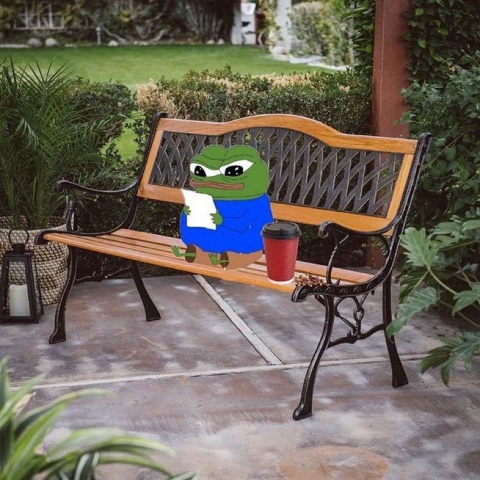 A Pepe the Frog meme edited to sit on a wooden park bench, holding a piece of paper and a red coffee cup, in a garden setting.