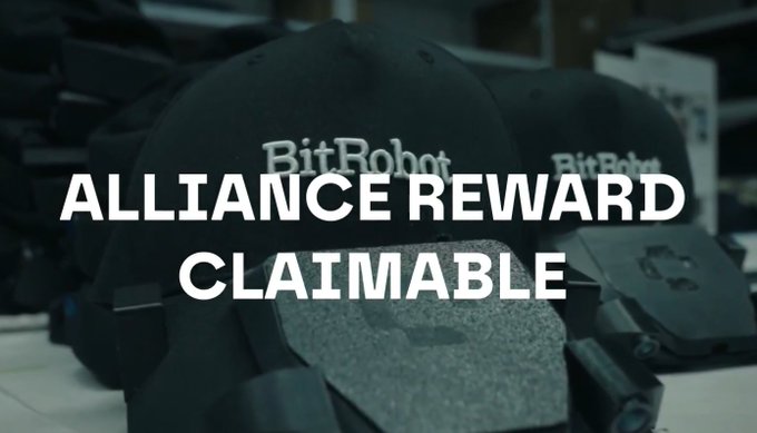 Two black baseball caps with "BitRobot" embroidered on them are displayed, overlaid with white text reading "ALLIANCE REWARD CLAIMABLE." The image relates to the post's announcement about BitRobot's new system and its alliance with Axis Robotics, highlighting the reward as a visual cue for the partnership benefits.