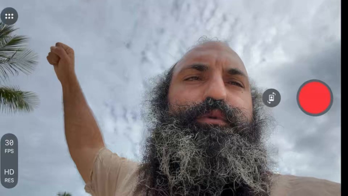 A selfie of a man with a beard holding up his arm.