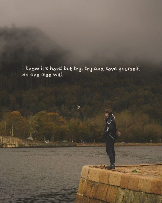 The image features a person standing at the edge of a body of water, possibly a lake or river, wearing a hoodie and holding a skateboard. The background includes trees and mountains, creating an outdoor setting for this scene. There are also some cars visible in the distance. The caption to the image reads: "I know its hard but try and save yourself. No one else will".