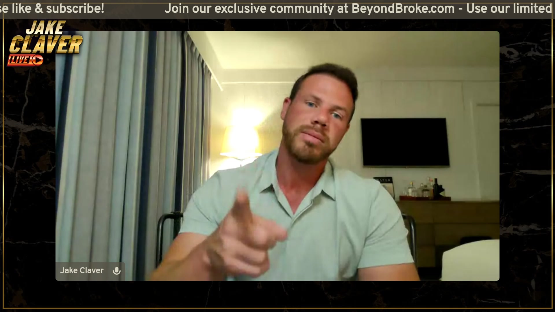 The image shows a man sitting at a desk, pointing his finger towards something off screen while wearing a grey shirt. The background of the image features a TV screen with text that reads "Jake Claver Live - XRP & Digital Assets Q&A Livestream". This suggests that the man is participating in an online Q&A session or a live streaming event related to Jake Claver's content, possibly discussing digital assets and their value.