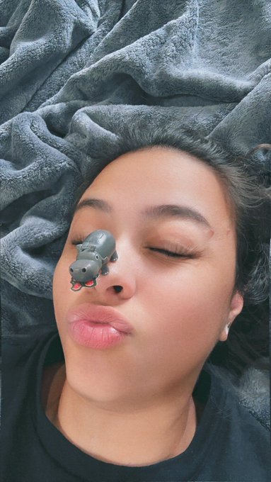 A selfie with a cartoon hippo filter over one eye accompanies the post, capturing the playful, "cute but ugly" vibe the poster describes. The gray blanket backdrop and casual black tee reinforce the candid, relatable tone of Day 174 in their "selfie a day until MON hits ATH" challenge.
