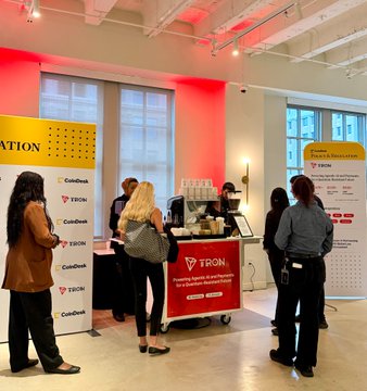 TRON and CoinDesk banners and signage are displayed at a Policy & Regulation event in Washington, D.C., where attendees gather around a TRON-branded coffee cart.