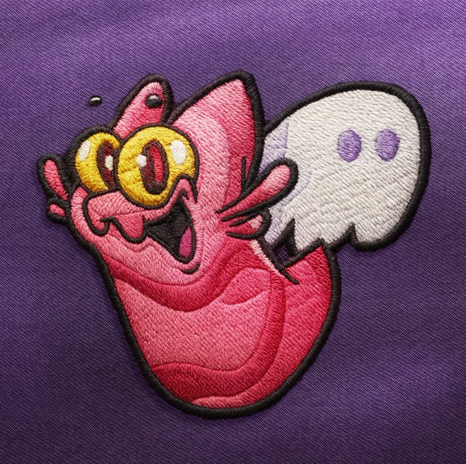 An embroidered patch depicting a pink, cyclops-like creature hugging a white ghost, set against a purple fabric background.