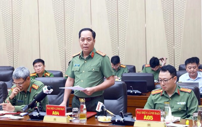 Vietnamese police officials in green uniforms holding a press conference, with nameplates reading "ĐẠI DIỆN LÃNH ĐẠO A04" and "ĐẠI DIỆN LÃNH ĐẠO A05" visible on the desk.