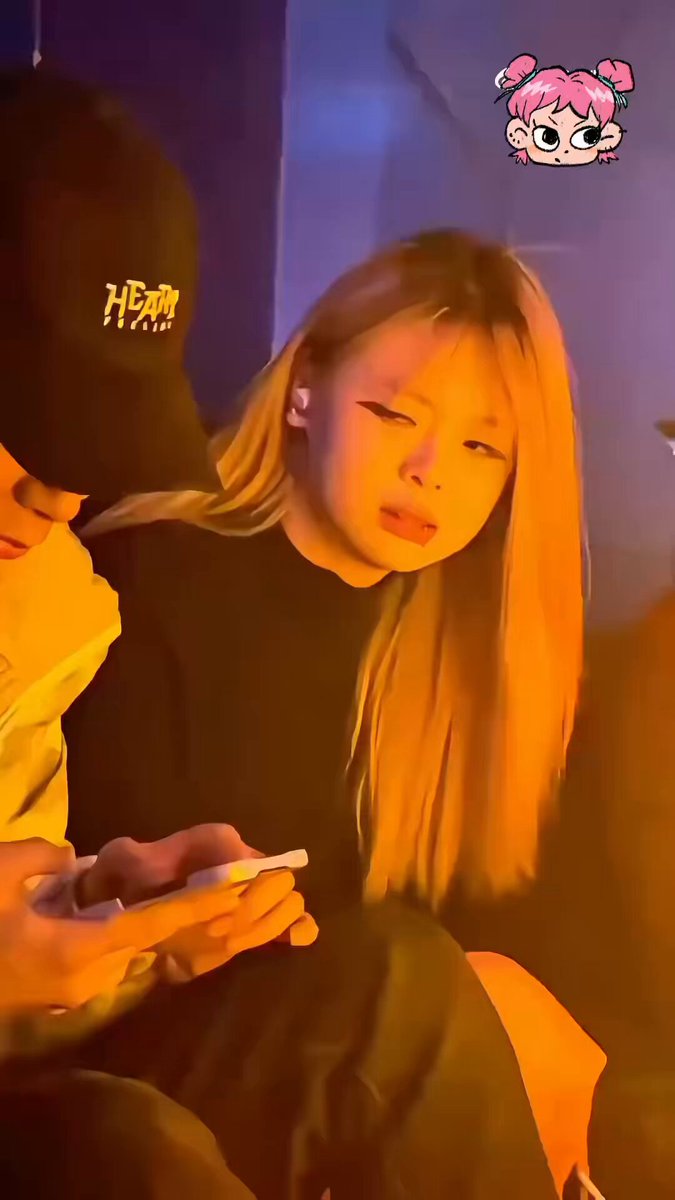 In this image, a person wearing a black baseball cap is holding a cellphone while seated with their legs crossed. The image also includes text that refers to the girl as an "obsessed fan" or "enthusiastic fan," suggesting that she might be an avid admirer of someone in the post. There are no visible texts about other people, and it seems that the focus is solely on the person wearing the cap and their cellphone usage.