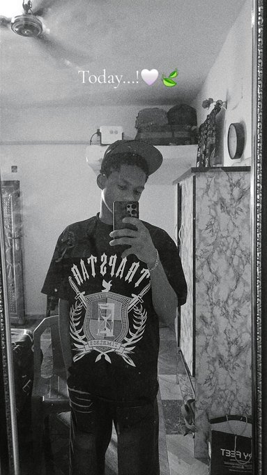 A black-and-white mirror selfie shows a young man wearing a backwards cap and a T-shirt featuring an "International Trademark" crest with ribcage graphics, captioned "Today...! 🤍🌿" — posted as a relaxed "gm" greeting to ask the community how they're making money today.