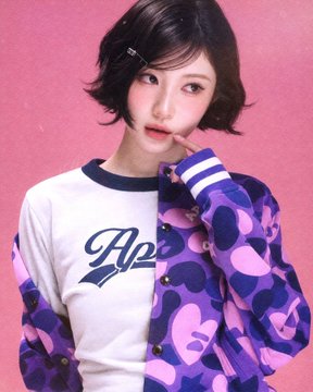A portrait of a young woman with short dark hair wearing a white shirt with blue trim and 'A2' text, layered under a purple jacket with a heart pattern, against a pink background.