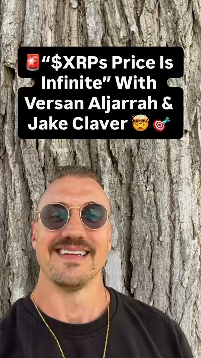 The image features a man wearing sunglasses and a gold chain necklace standing next to a tree trunk. The background of the image is white, which contrasts with the dark colors of the man's attire and the tree trunk. There are no texts or other objects in the image besides these elements.