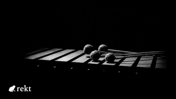Four mallets rest on the keys of a marimba in stark black and white lighting, with the "rekt" logo in the bottom corner—symbolizing how the Harmony Protocol was "struck" again, losing an estimated $3.2M due to unauthenticated proof fields allowing replay of cross-shard receipts and an unauthorized 4B ONE mint.