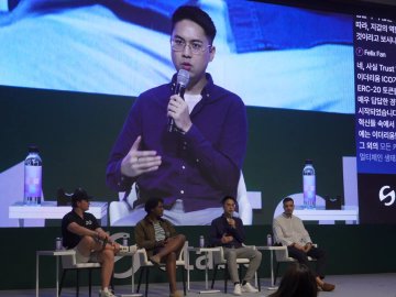A panel discussion featuring four men seated on stools in front of a large screen displaying a man speaking into a microphone, with Korean text and 'Pedro Yunta' visible on the side.