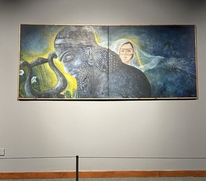 A large two-panel painting displayed on a gallery wall features a serene stone Buddha figure with a lyre on the left and a bespectacled woman draped in a flowing veil on the right, set against moody blue and yellow tones. The artwork's tranquil yet striking imagery embodies the post's well-wish of wishing viewers a week as "beautiful as this art."