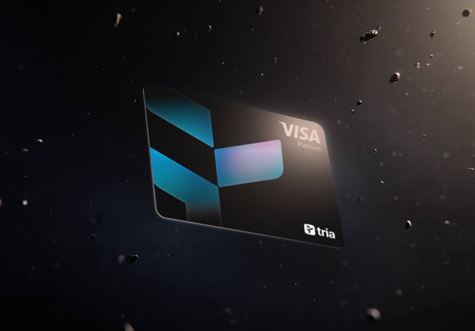 The image features a black Visa credit card with a blue and purple design on its front. The card has a unique shape resembling a triangle or diamond, which makes it stand out against the dark background of space. The text "Visa" is clearly visible on the card, indicating that it's a Visa credit card. The post also mentions that users can earn cashback and yields by using their Tria Card at the mall for real-life payments. This implies that the image might be promoting the use of the Tria Card as an alternative to traditional credit cards or bank accounts.
