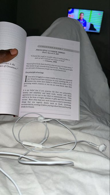 A person reads a book open to Chapter Four titled 'Principle Number Three: Don't Speed It Up' in bed while wearing earphones, with a TV playing in the background.