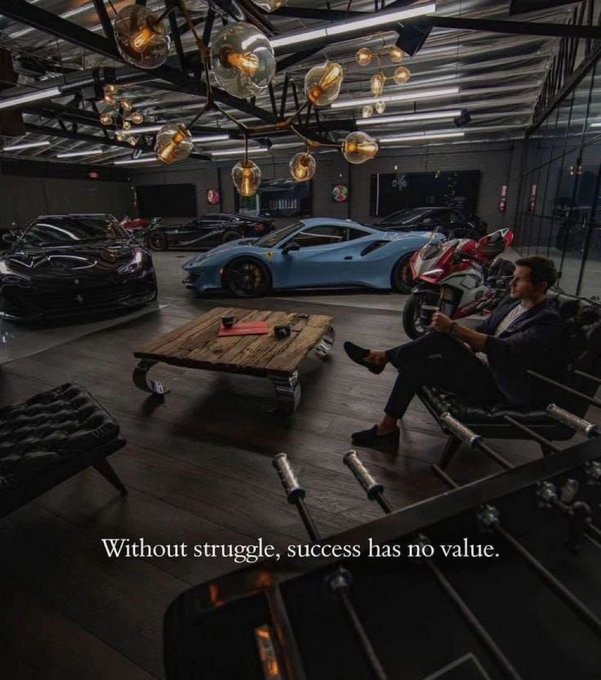 A man in a suit sits in a chair in a luxurious garage filled with high-end cars and a motorcycle, with text reading 'Without struggle, success has no value.'